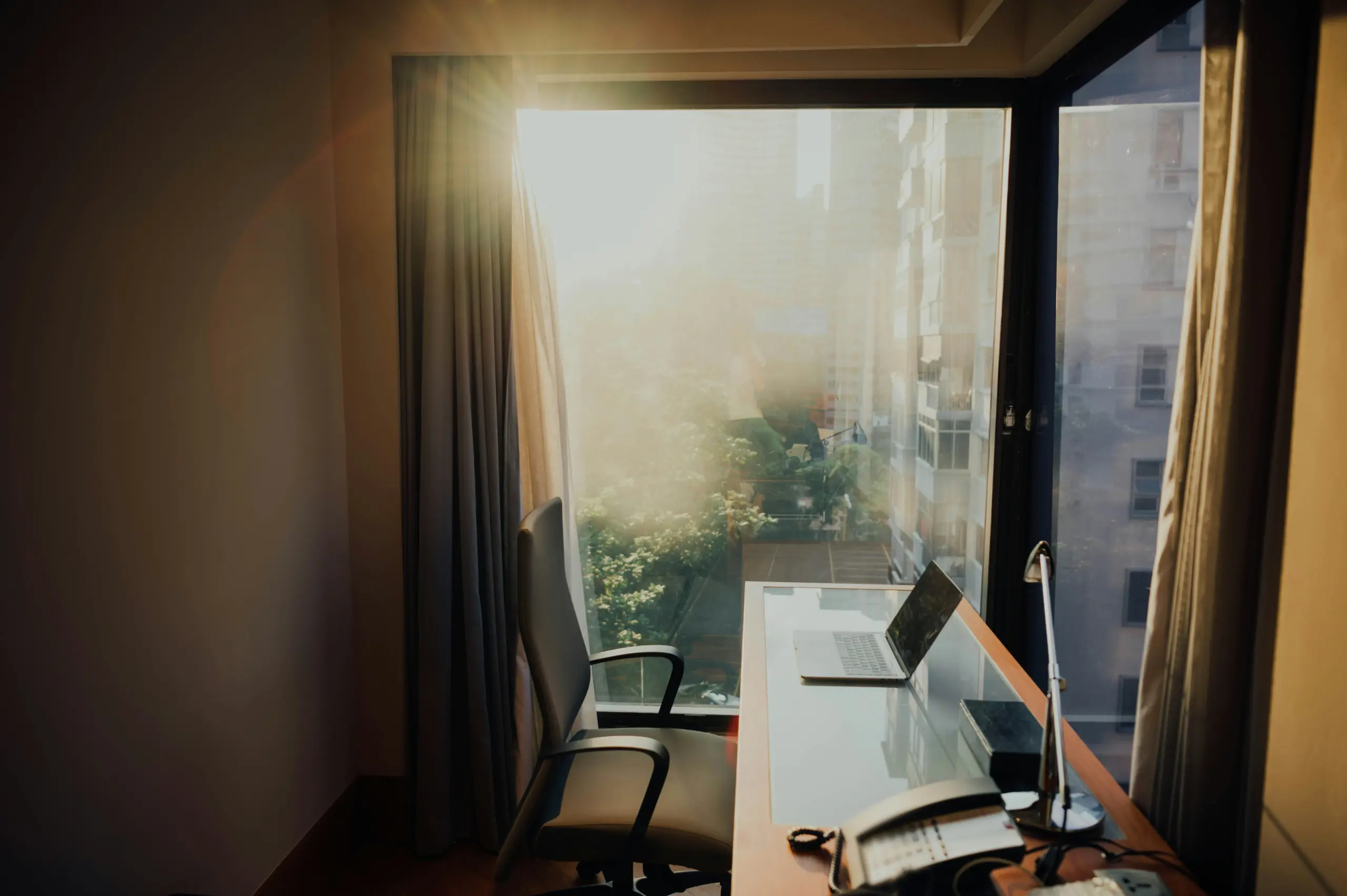Open laptop on a quiet desk beside a sunlit window